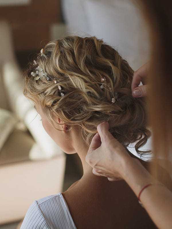 Stylist arranging intricate bridal hairstyle with decorative pins.