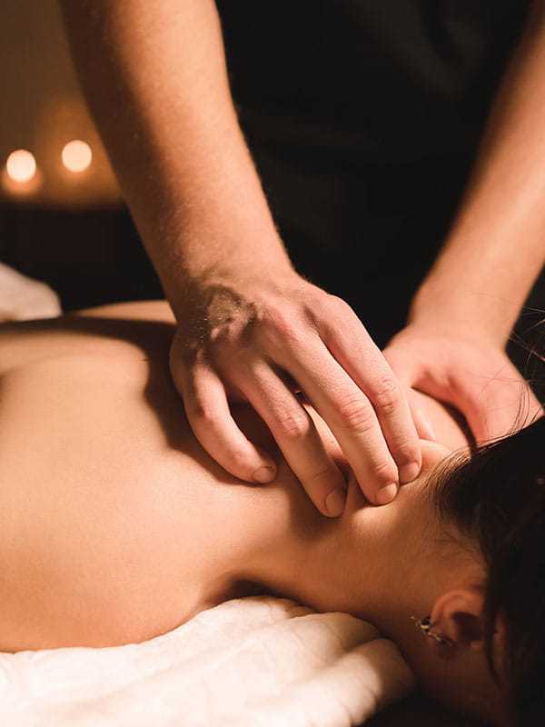 Person receiving a relaxing back massage in a dimly lit spa setting.